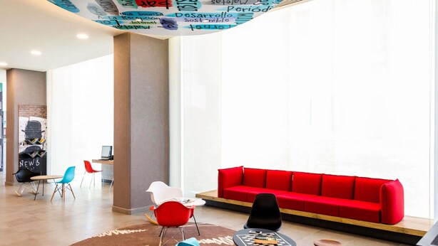 A modern lobby with a red sofa, colorful chairs, a round table, and a ceiling with various words and phrases. - ibis Mexico Tlalnepantla (Tlalnepantla de Baz)