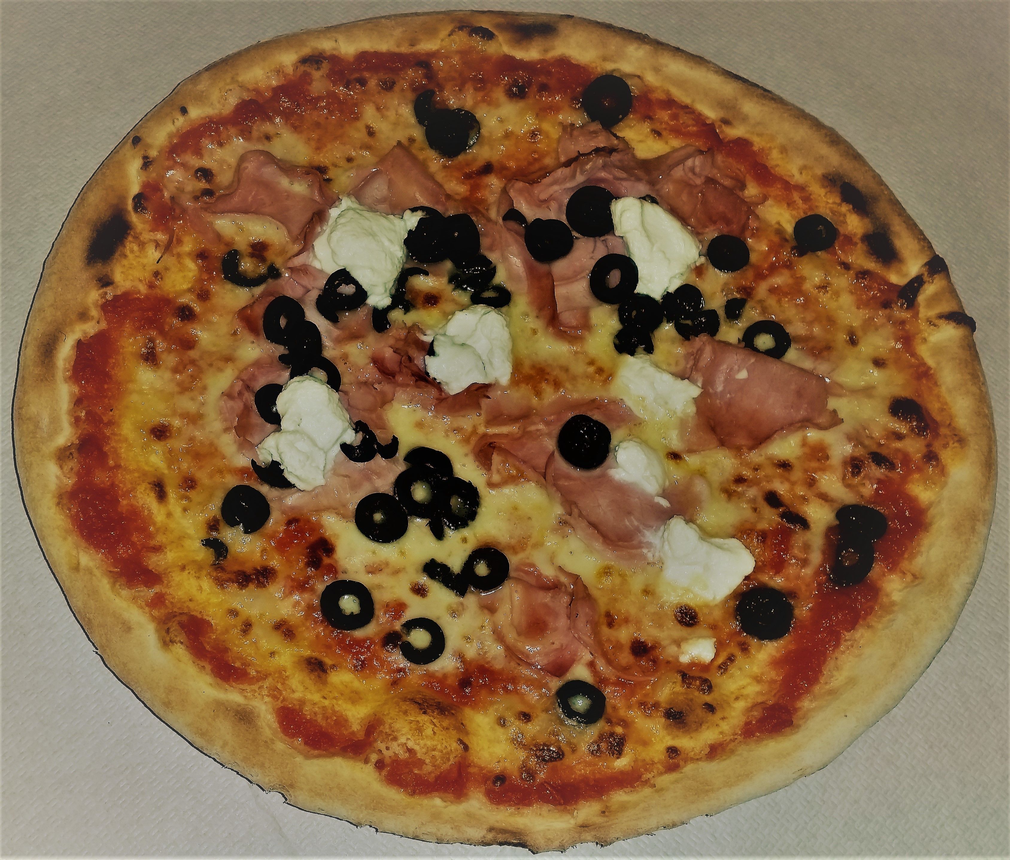 Pizza con jamón, aceitunas negras y queso sobre fondo liso.