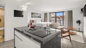 A modern hotel room with a kitchen island, a bed, a sofa, and a large window with a city view. - Armonik Suites (Mexico City)
