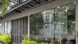 A modern building with large windows, a metal staircase, and green plants in front. - Armonik Suites (Mexico City)