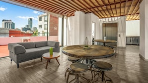 A modern interior with a sofa, round dining table, and a city view. - Armonik Suites (Mexico City)