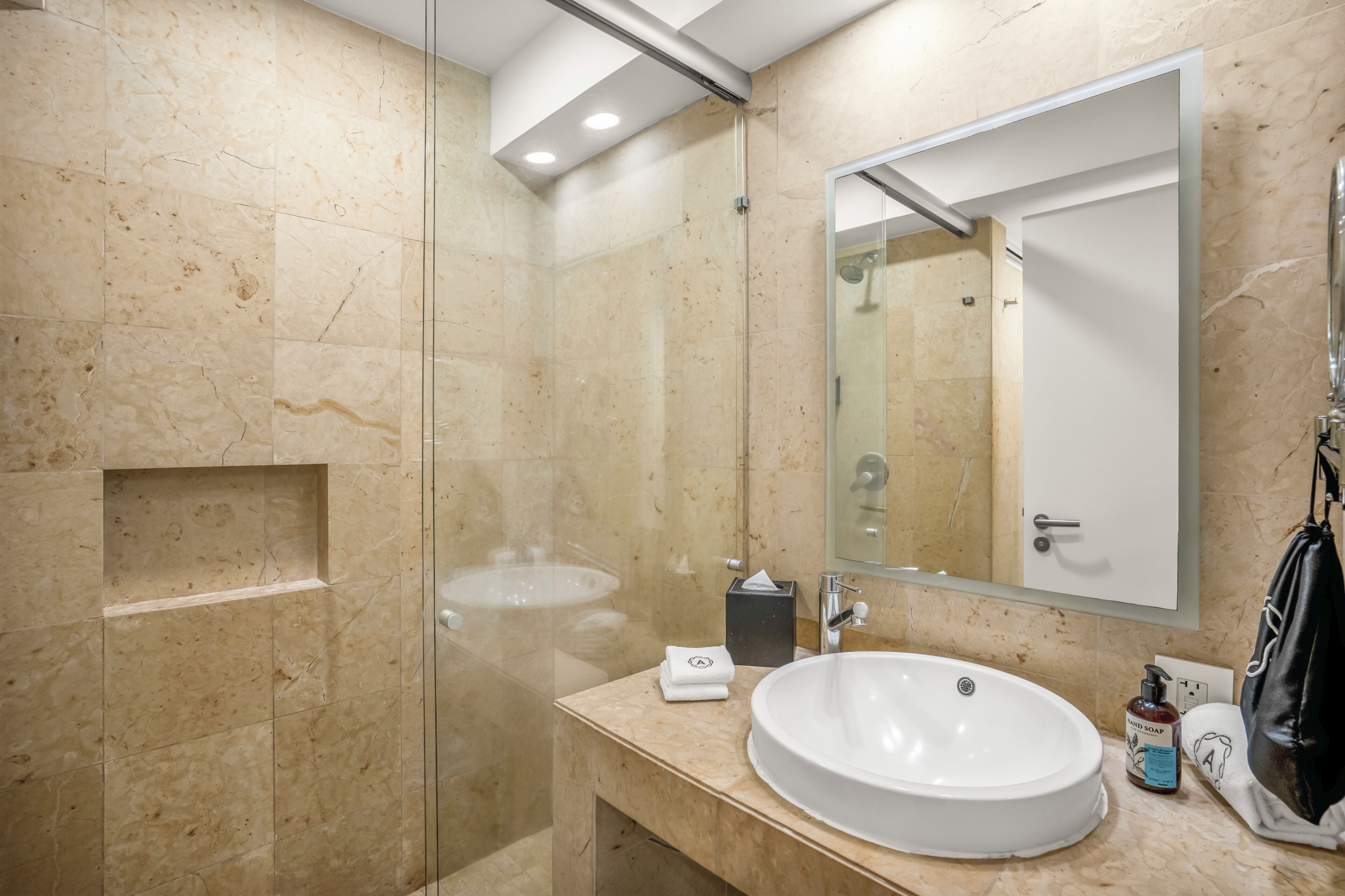 A modern bathroom with a glass-enclosed shower, a white sink, and a large mirror.
