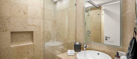 A modern bathroom with a glass-enclosed shower, a white sink, and a large mirror.