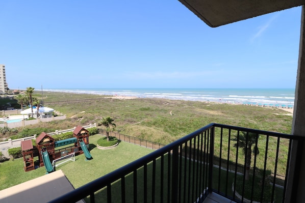 Ein Balkon mit Blick auf einen Strand und einen Spielplatz.