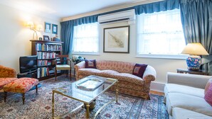 A living room with a sofa, armchairs, a coffee table, a bookshelf, and a television.