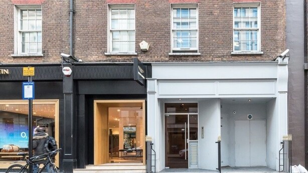 A building with a white facade, a garage door, and a storefront with a sign.