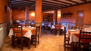 Ein Restaurant mit Holztischen und -stühlen, einem Kachelboden und einer hohen Decke mit freiliegenden Balken.