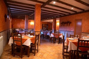 A restaurant with wooden tables and chairs, a tiled floor, and a high ceiling with exposed beams.