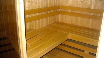 A sauna with wooden benches and a sloped floor.