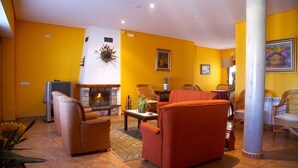 Ein Wohnzimmer mit Kamin, gelben Wänden und Korbmöbeln.