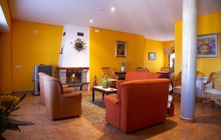 A living room with a fireplace, yellow walls, and wicker furniture.