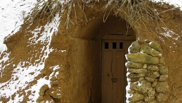 A traditional stone hut with a wooden door and a thatched roof.