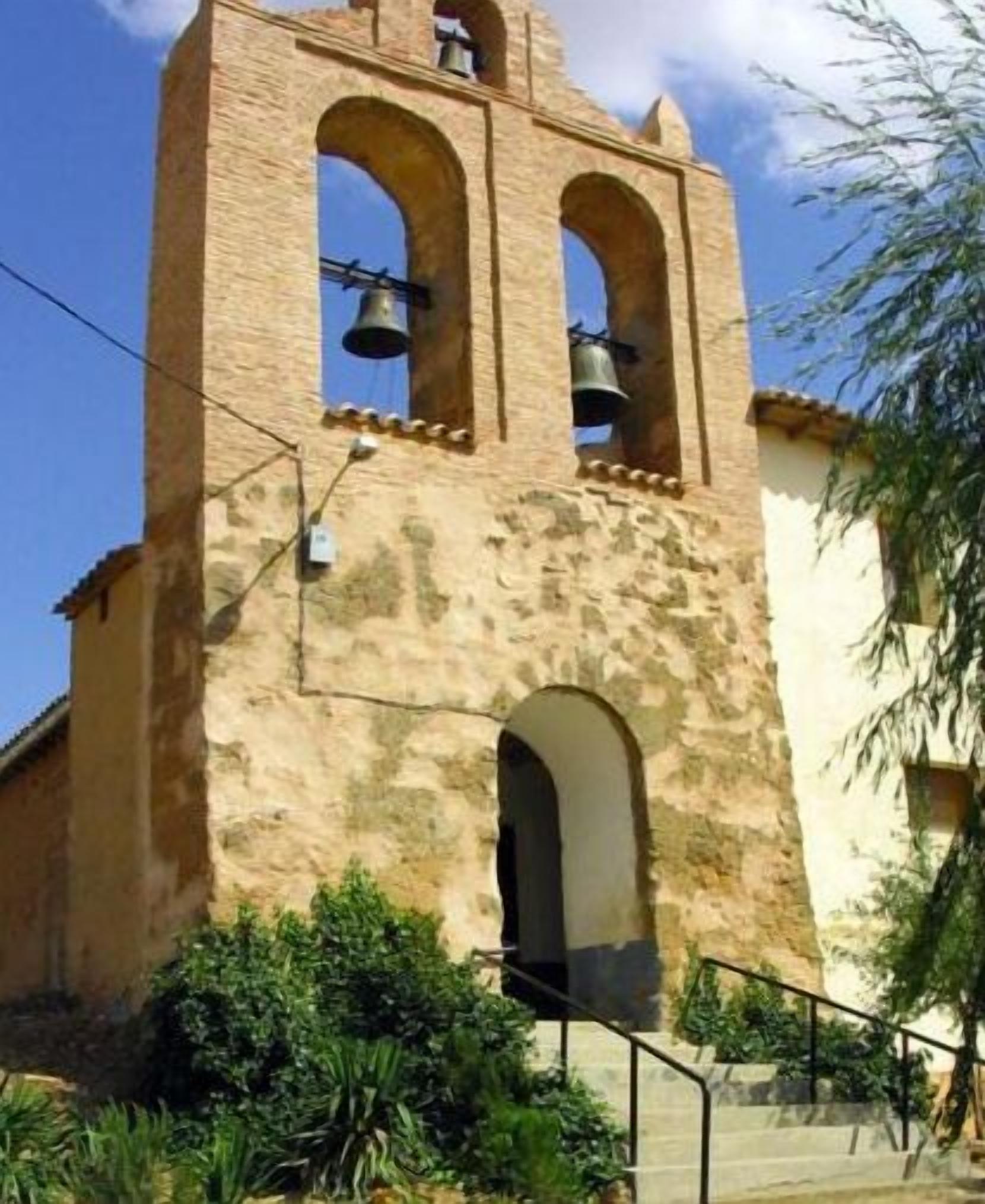 Un edificio histórico con una torre de campanas, ventanas de arco y una escalera que conduce a la entrada.