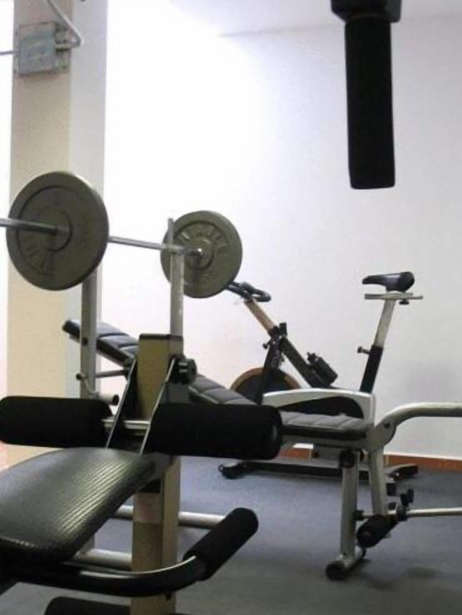 A gym with exercise equipment including a bench, a weight bench, and a stationary bike.