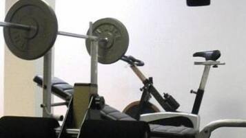 A gym with exercise equipment including a bench, a weight bench, and a stationary bike.