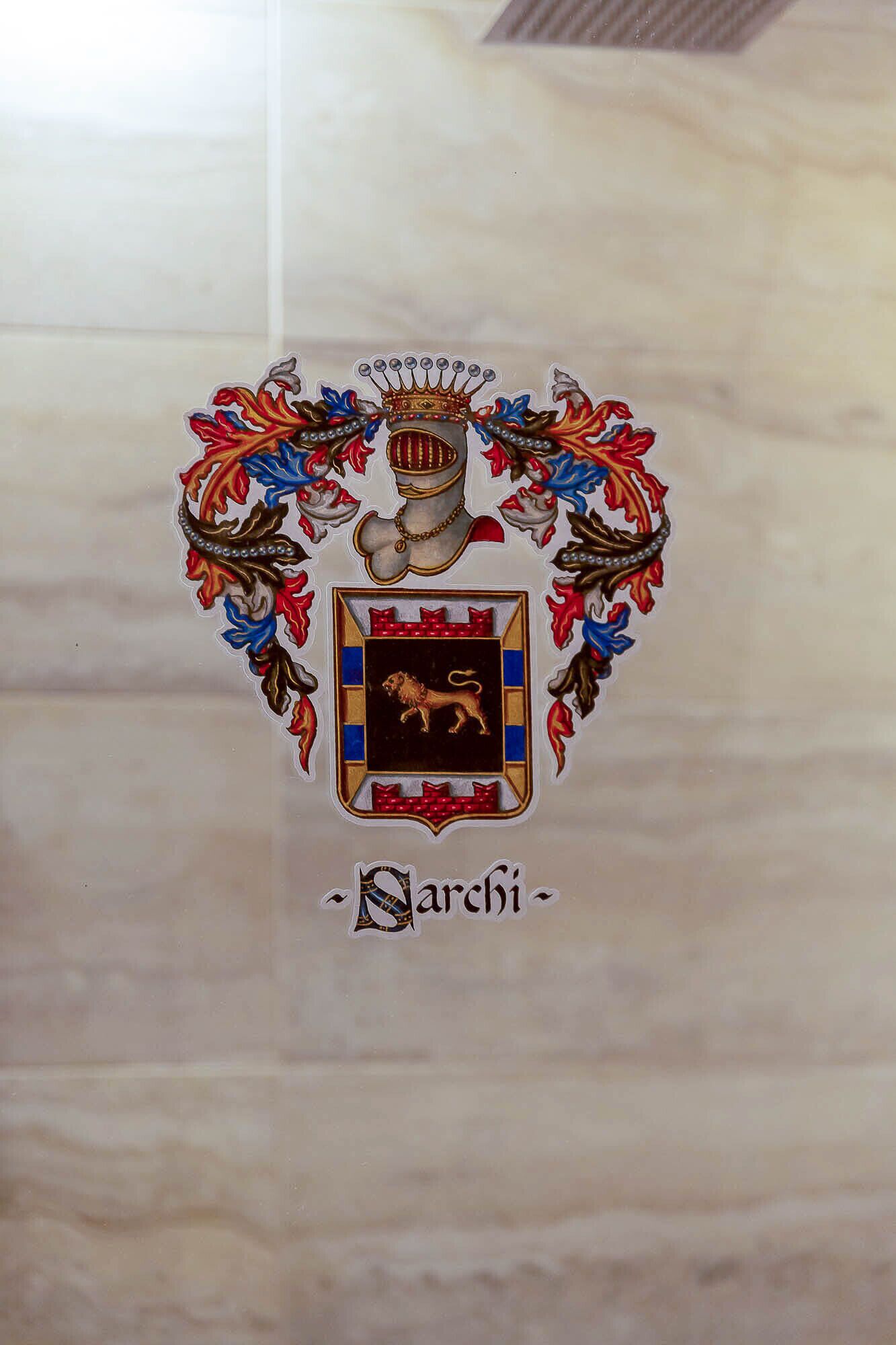 Un escudo heráldico con un león y una corona, rodeado de detalles florales ornamentales.