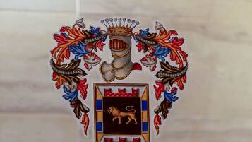 Un escudo heráldico con un león y una corona, rodeado de detalles florales ornamentales.