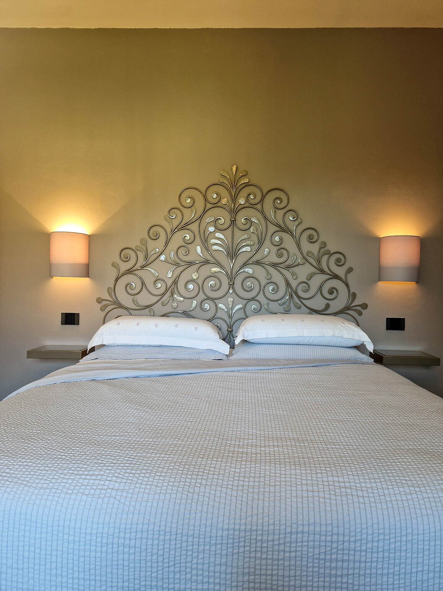 Een slaapkamer met een groot bed, twee nachtkastjes en wandlampen.