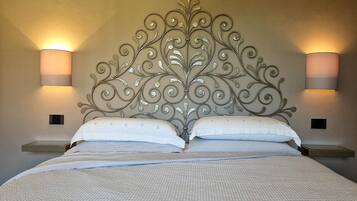 Un dormitorio con una cama grande, dos mesitas de noche y lámparas fijadas a la pared.