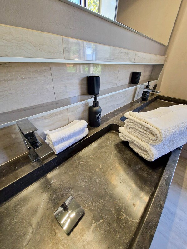 A modern bathroom with a stainless steel sink, a towel warmer, and a soap dispenser. - Villa Sarchi (Grantola)