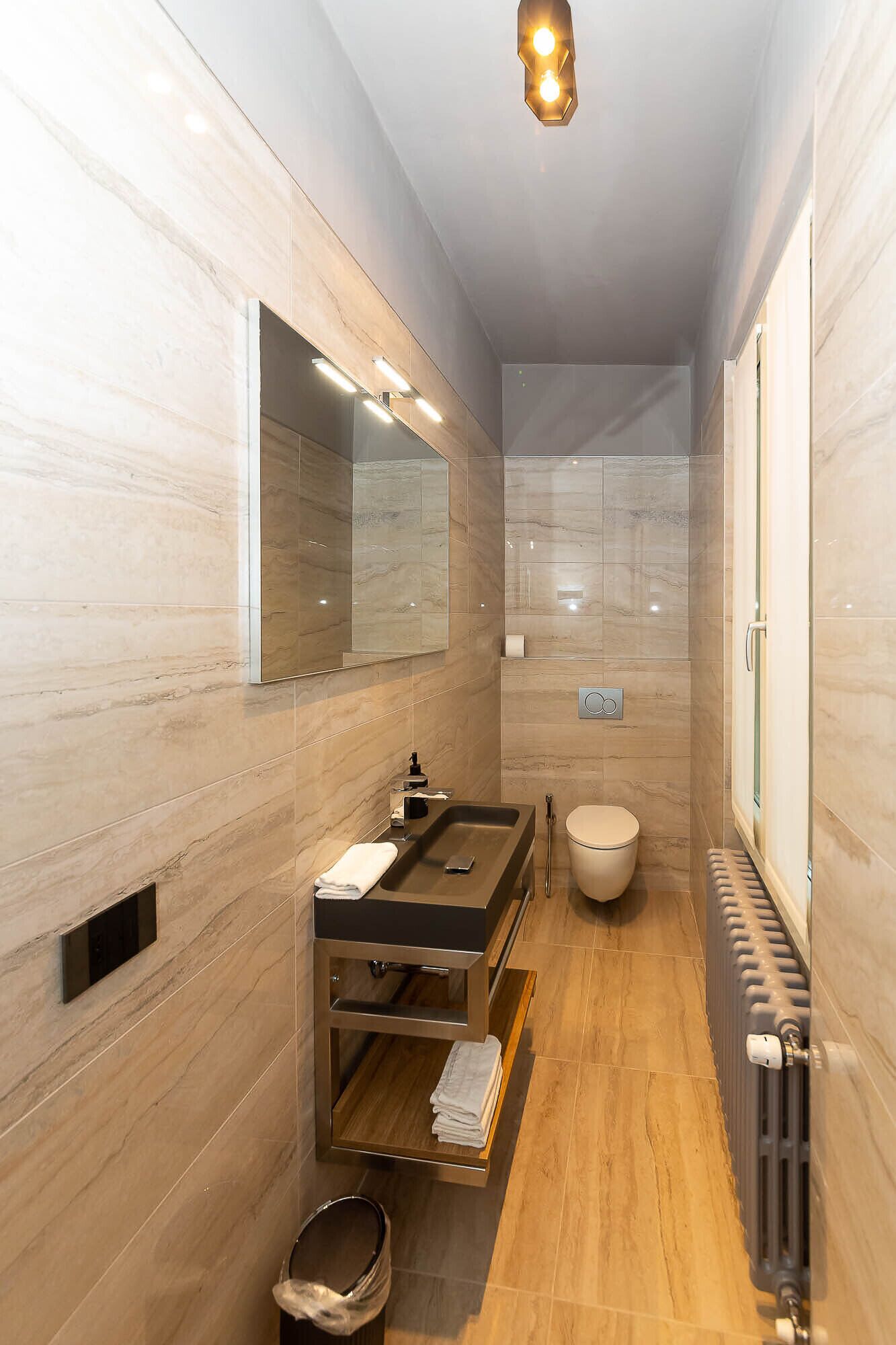 A modern bathroom with a large mirror, a sink with a vanity, a toilet, and a shower area.