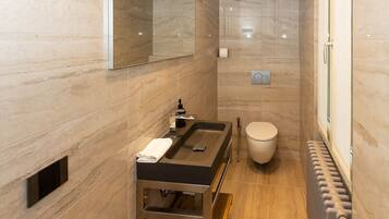 A modern bathroom with a large mirror, a sink with a vanity, a toilet, and a shower area.
