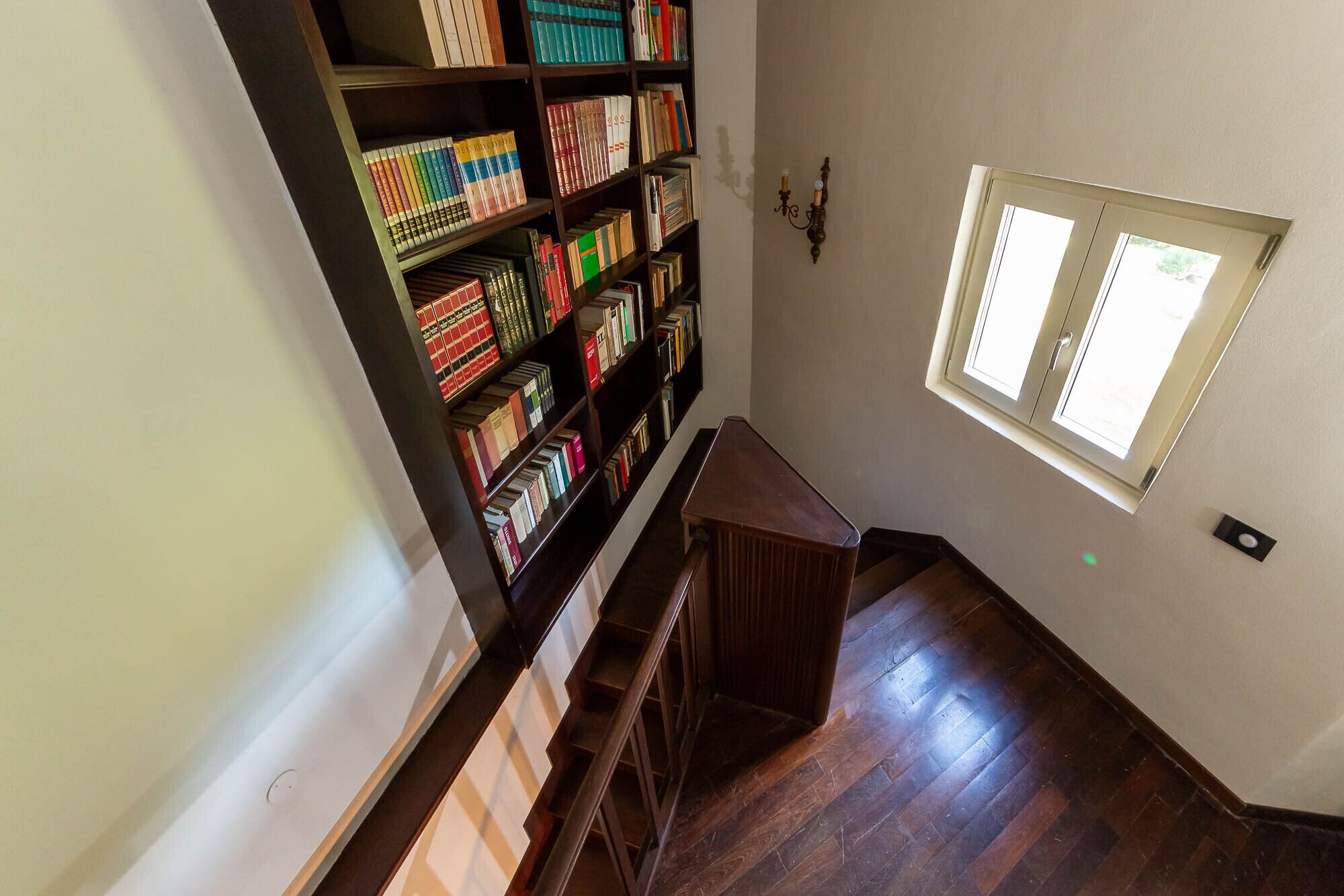 A staircase leading to a landing with a bookshelf filled with books.