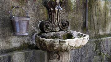 A stone fountain with a metal bucket attached to a wall.
