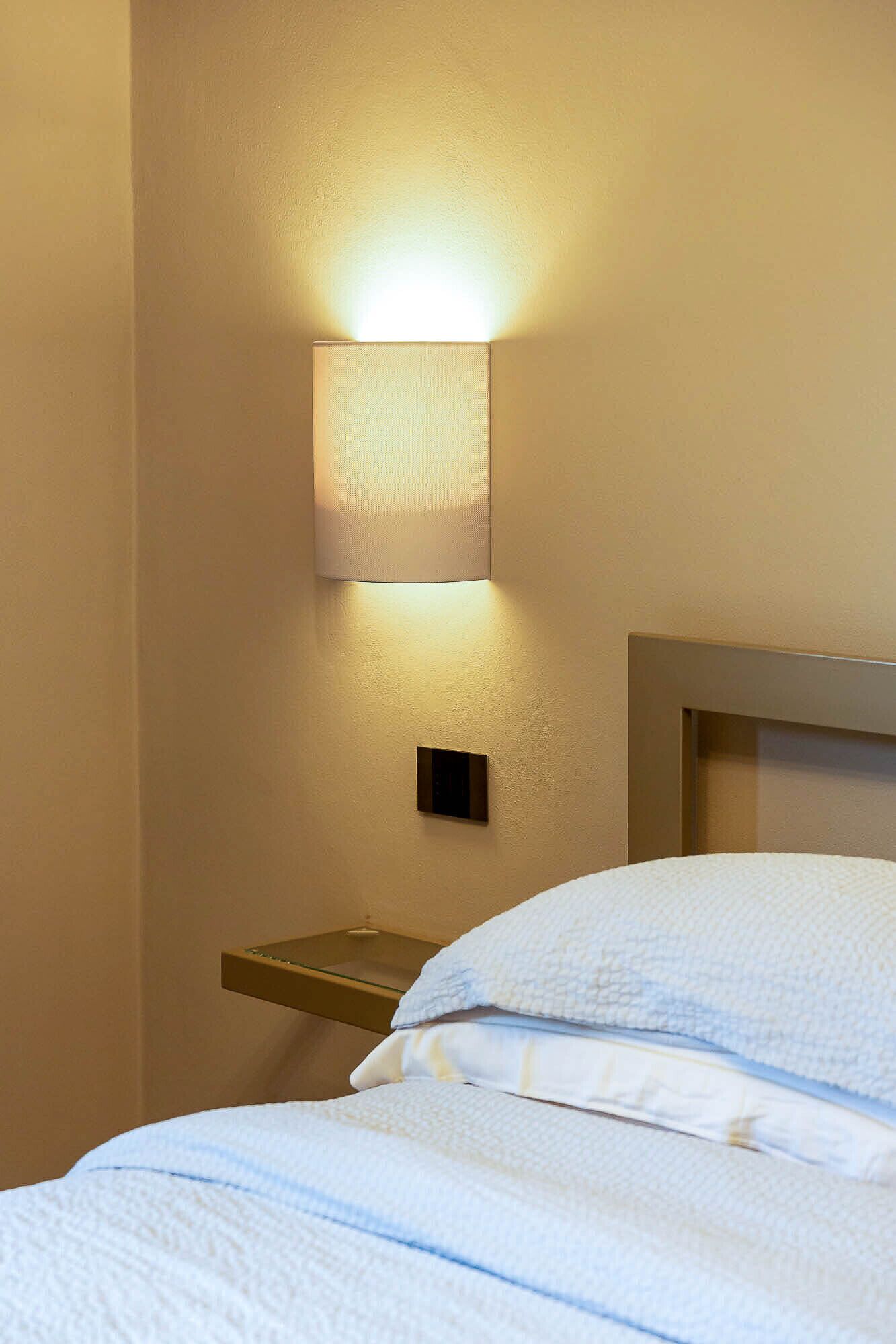 Ein Hotelzimmer mit einem Bett, einem Nachttisch und einer Wandlampe.