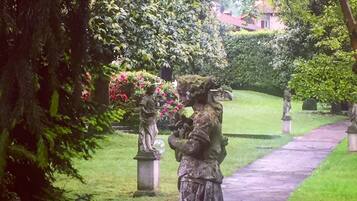 Um caminho no jardim com estátuas e vegetação exuberante.