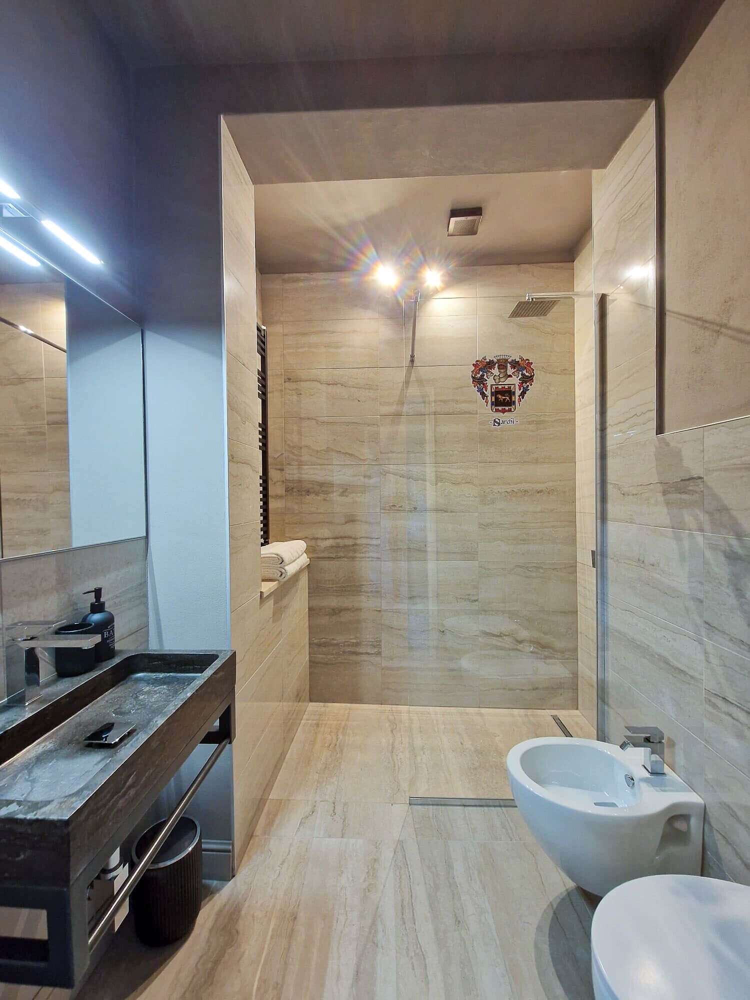 A modern bathroom with a shower, a sink, and a toilet.