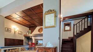 Un vaste espace de vie agrémenté d’une cheminée, de meubles en bois et d’un escalier menant à un autre niveau.