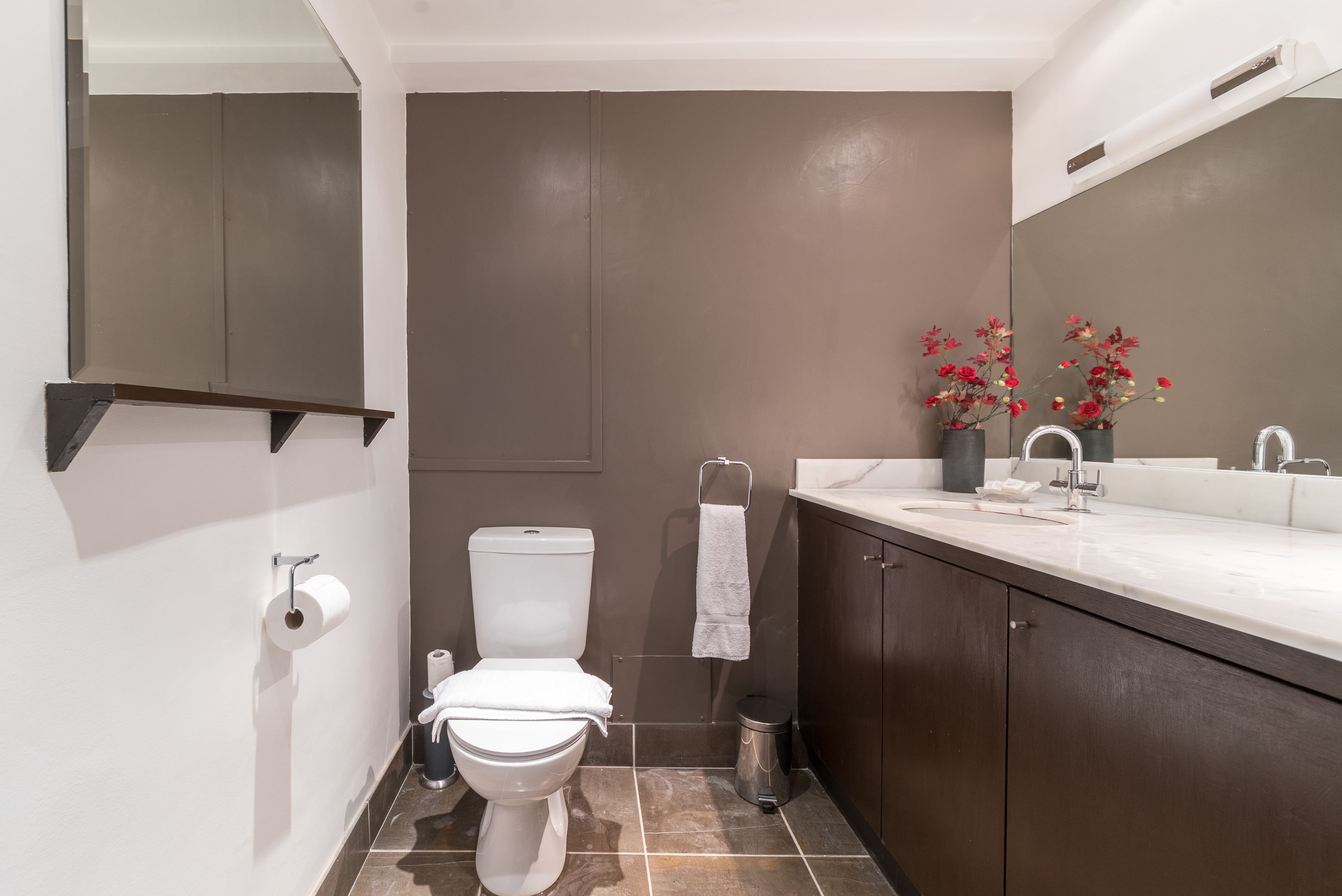 Ein modernes Badezimmer mit Toilette, Waschbecken und Spiegel.