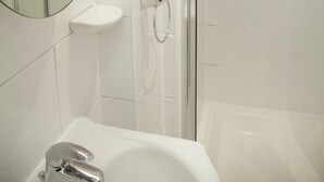 A bathroom with a glass-enclosed shower, a round mirror, and a white sink. - A Place Like Home - Inviting Flat near South Kensington (London)