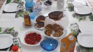 Ein Tisch reichhaltig mit Speisen gedeckt, darunter Früchte, Gebäck und Beilagen, was auf ein Frühstück oder einen Imbiss hindeutet.