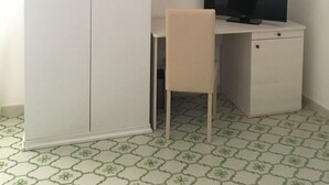 Ein Zimmer mit einem weißen Kleiderschrank, einem Schreibtisch mit Stuhl und einem Fernseher.