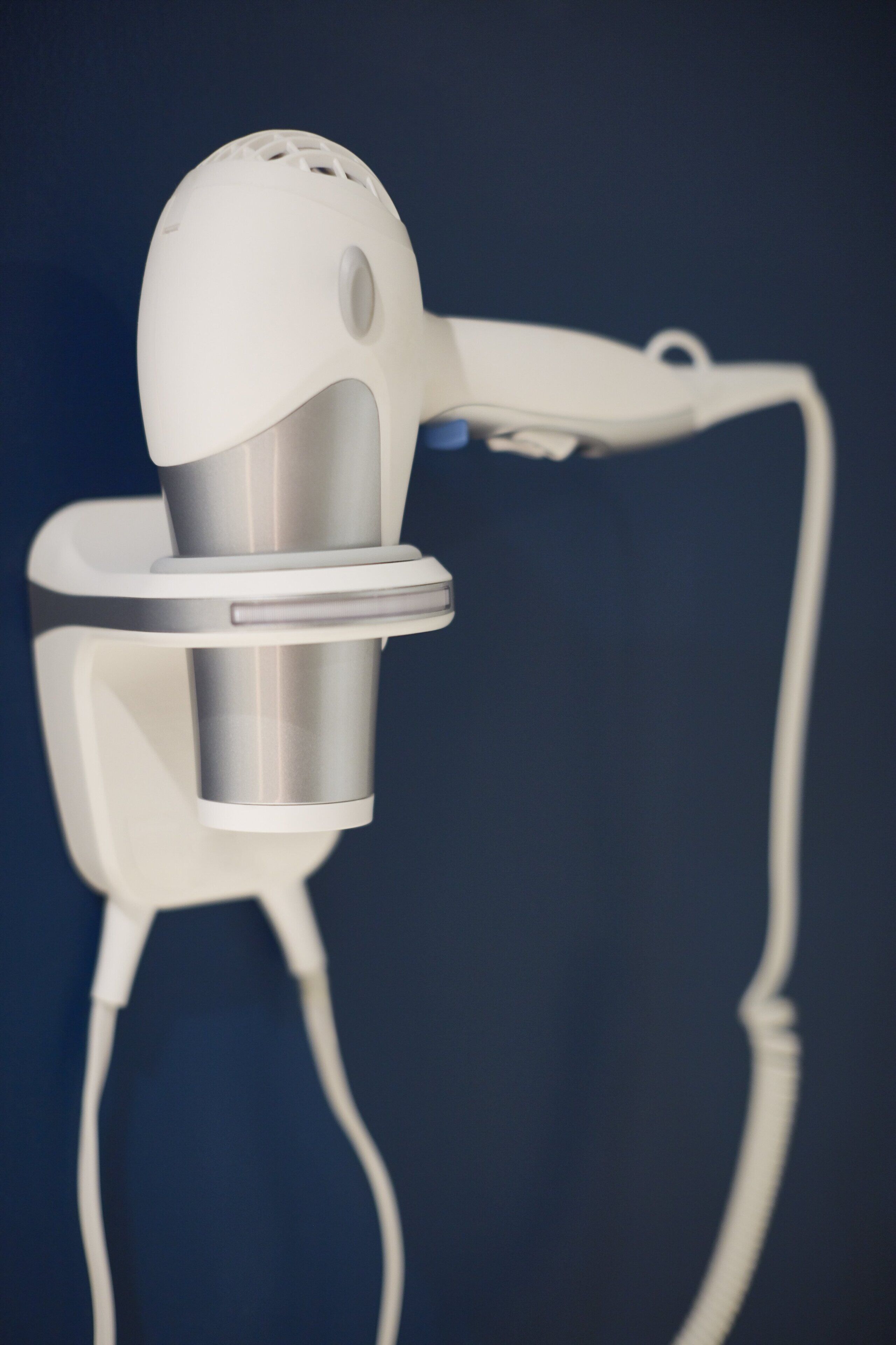 A white hair dryer with a cord.