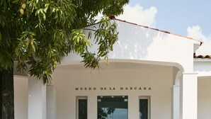 The exterior of Museo de la Mascara with a clear entrance, white walls, and a tree in the foreground. - One Acapulco Diamante (Acapulco)