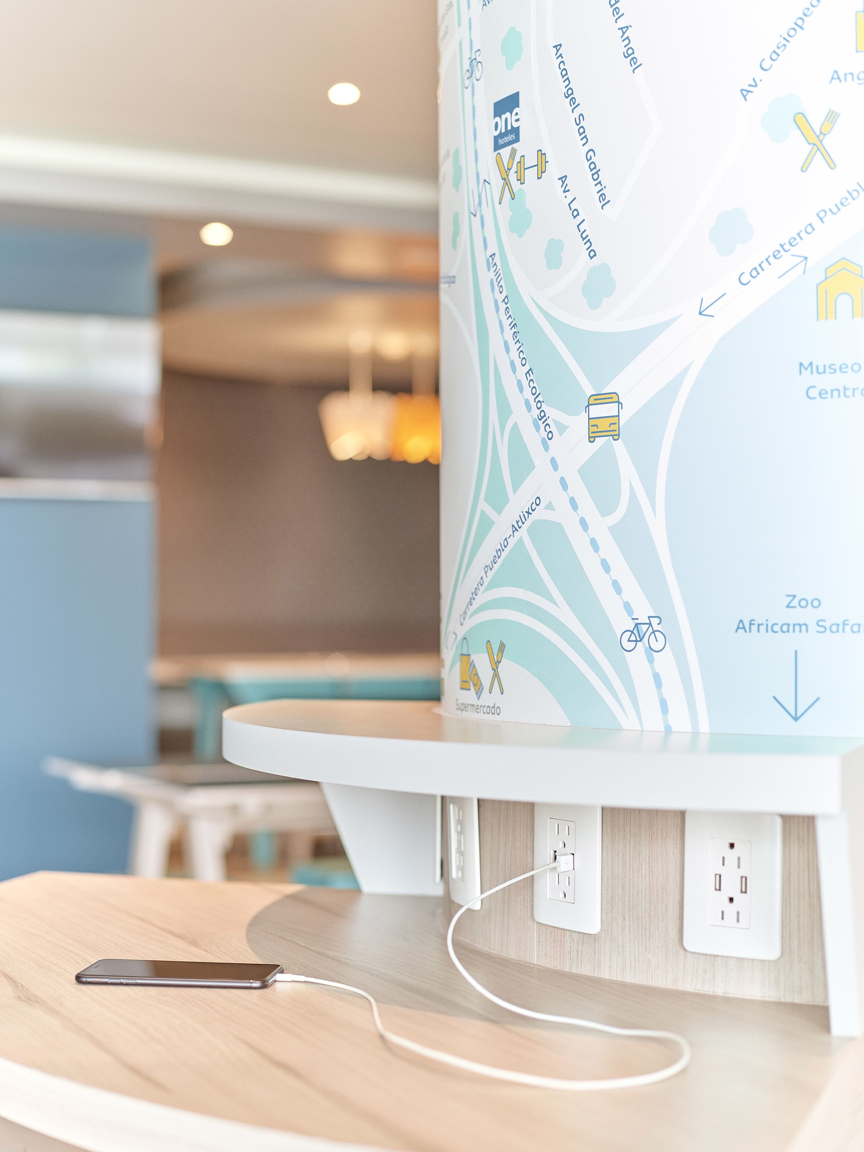 A map on a wall with a smartphone charging on a table.