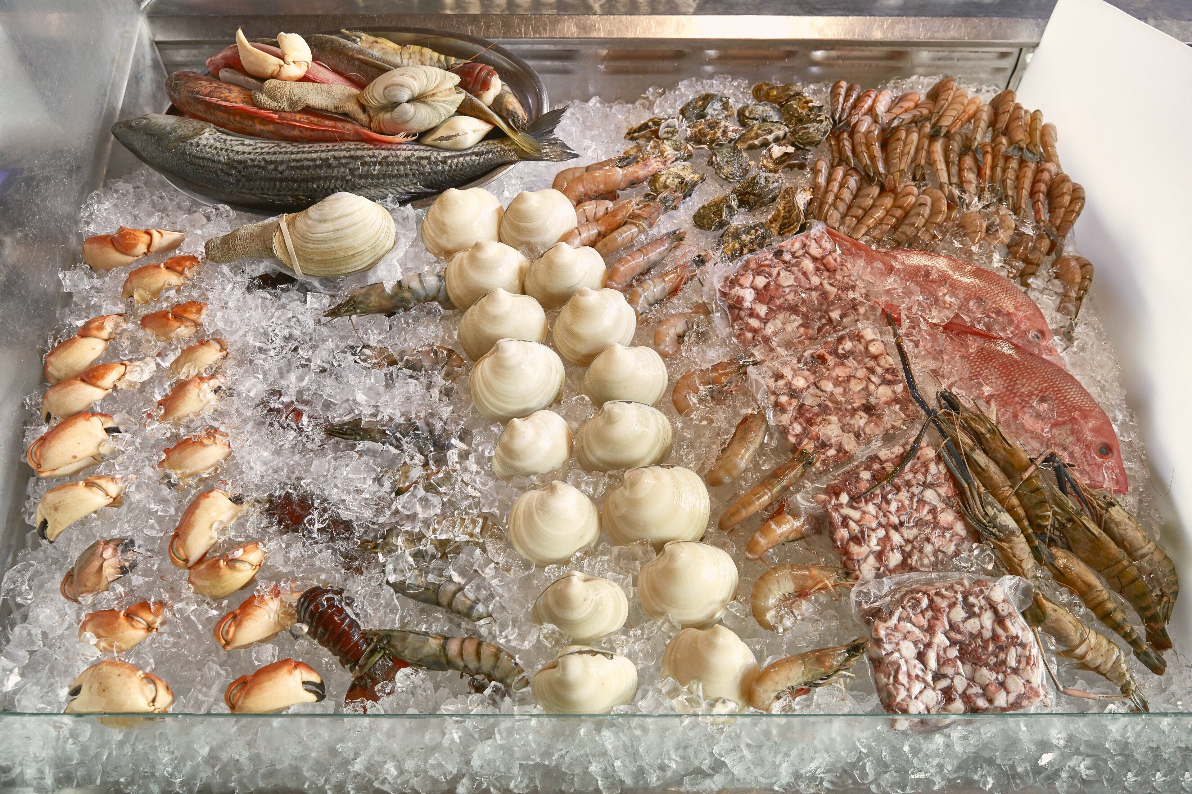 A variety of seafood on ice, including shrimp, clams, and fish.