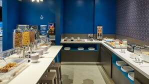 A modern breakfast bar with a variety of food options, including cereal, fruits, and beverages, with a blue and gray color scheme. - One Acapulco Diamante (Acapulco)