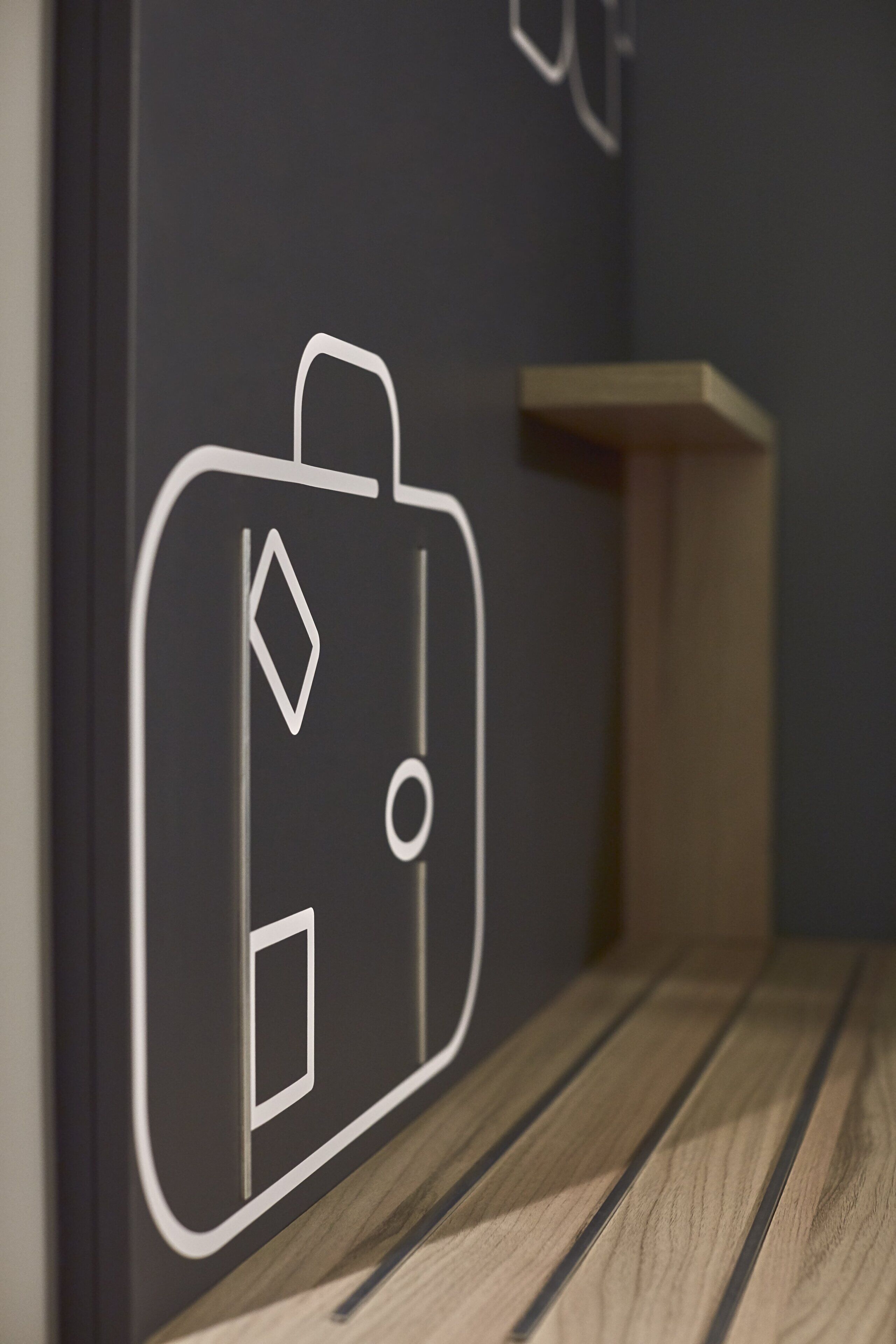 A wall with a geometric wall art of a suitcase.