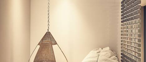 A room with a hanging chair, a bean bag, and a wall-mounted rack.