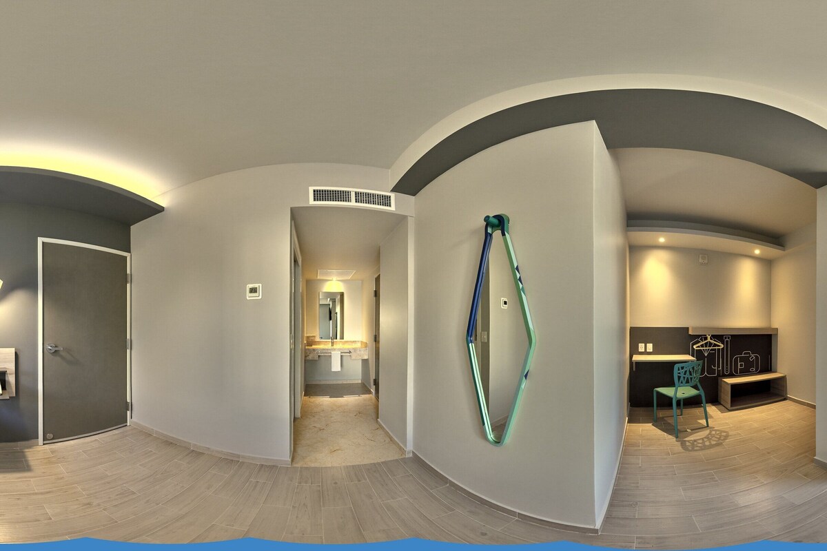 Habitación de hotel moderna con techo curvo, cama, zona de estar con una silla, chimenea y vistas al exterior.