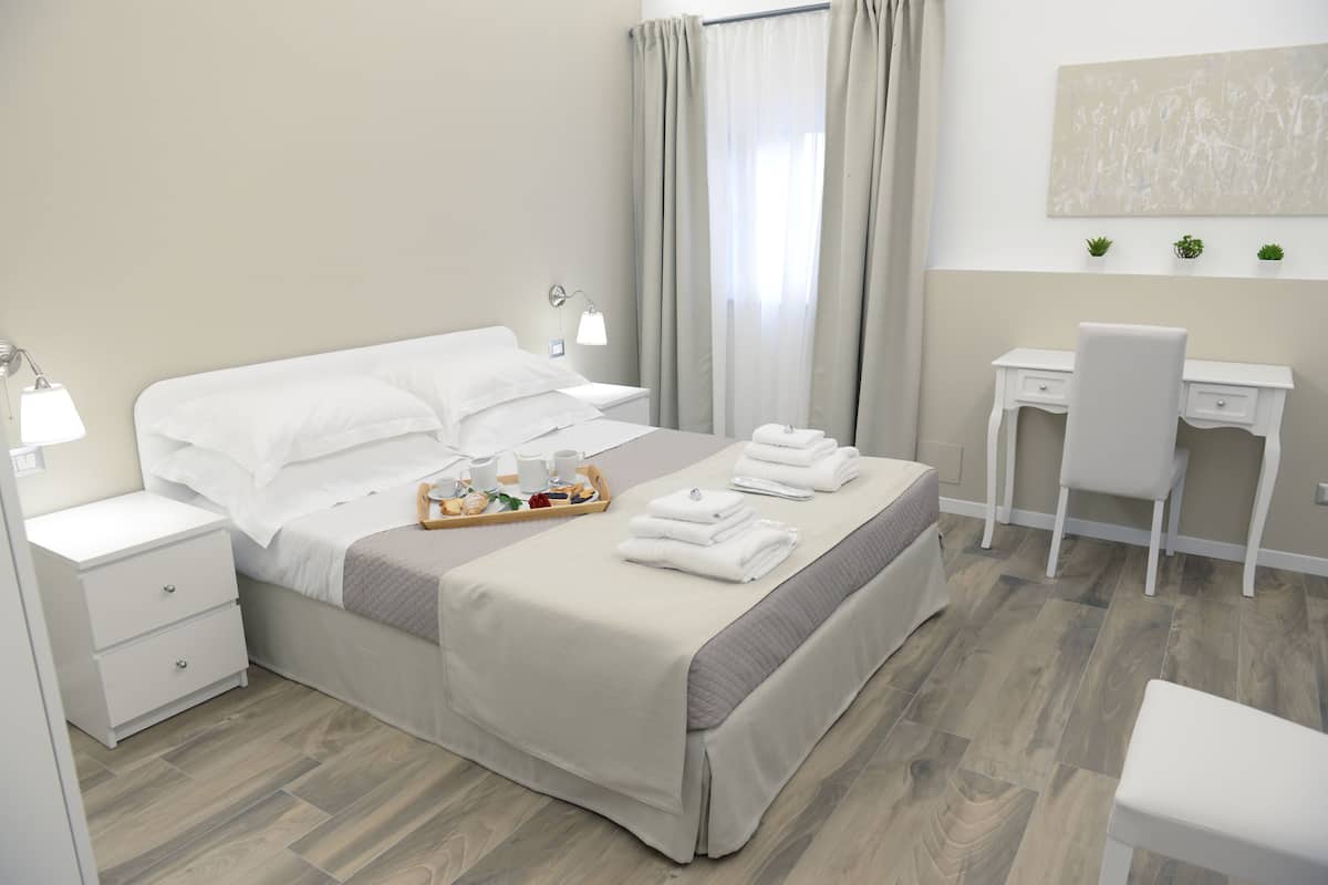 A hotel room with a bed, bedside tables, a desk, and a chair.