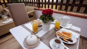 A breakfast table with a white teapot, two glasses of orange juice, a pitcher of orange juice, a plate with croissants and toast, a cup of coffee, and a vase with red flowers. - Domus Dams B&B (Montescaglioso)