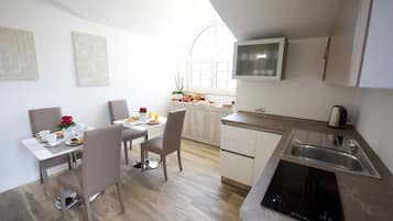 A modern kitchen with a dining area, white cabinetry, a built-in stove, and a window providing natural light.