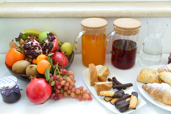 A table with a fruit bowl, two pitchers of beverages, a glass of water, and pastries. - Domus Dams B&B (Montescaglioso)