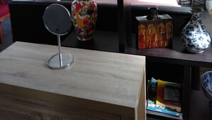 Ein Wohnzimmer mit Couchtisch aus Holz, einer Blumenvase, einem dekorativen Spiegel und einem Bücherregal.