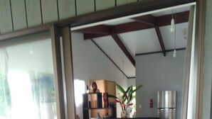 Ein Schlafzimmer mit einem Bett, einer Glastür, die auf einen Balkon führt, und einer Küchenzeile im Hintergrund.